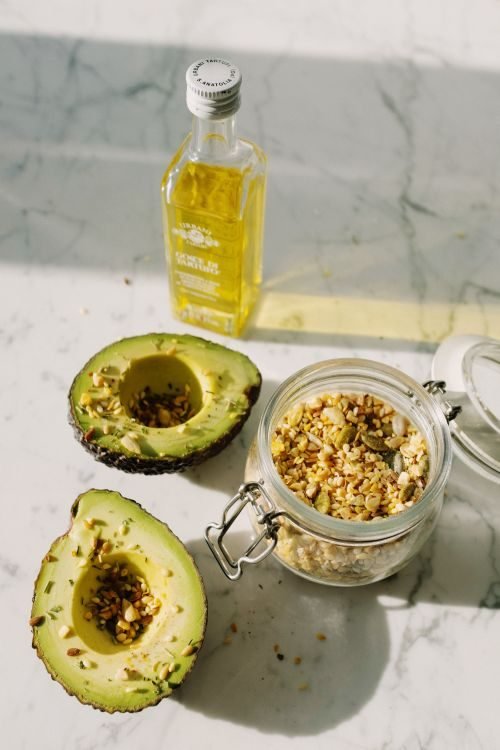 Avocado oil bottle with fresh avocados
